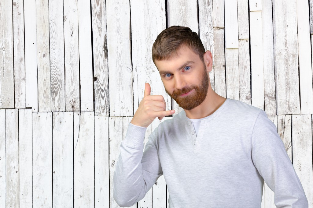 Young man using a call me gesture