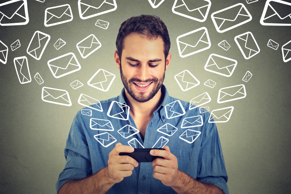 Portrait young happy man busy sending messages emails from smart phone