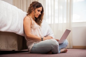 Beautiful Hispanic brunette using her laptop computer to work while sitting in a hotel room