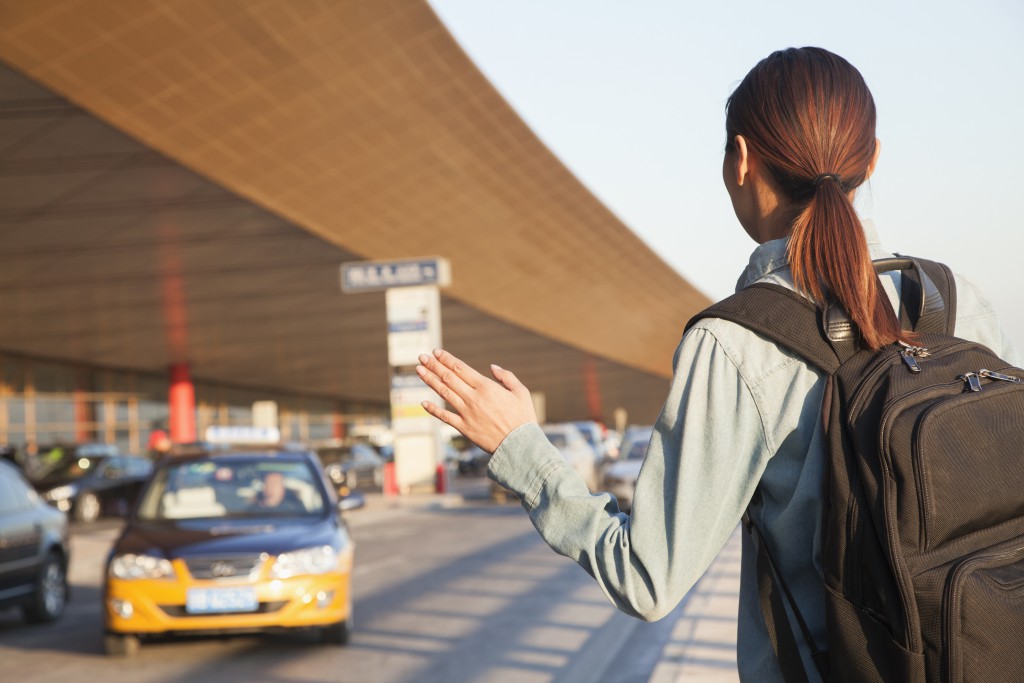 Young traveler hailing a taxi at airport